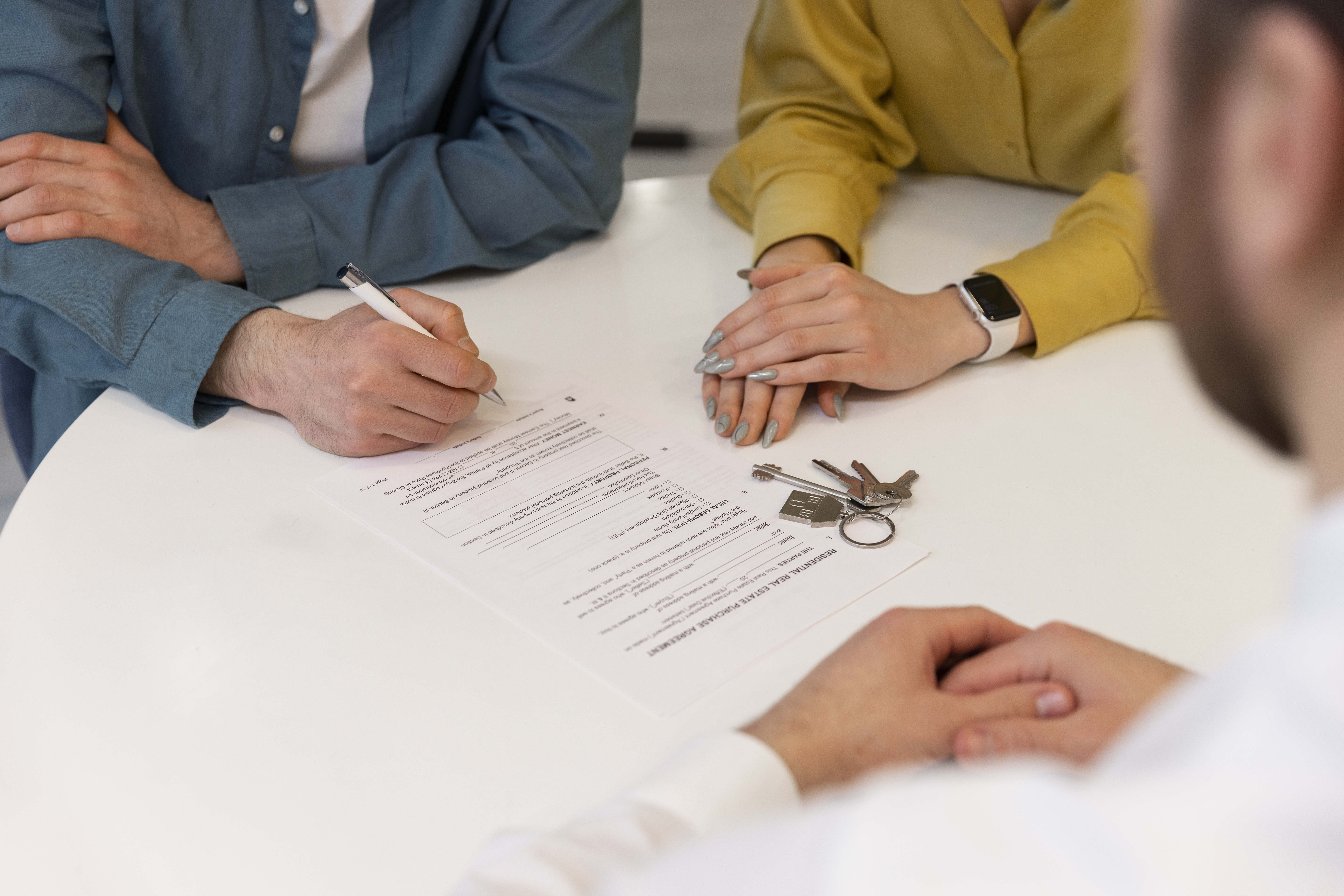 Couple signing real estate paperwork with house keys on the table, selling a property in probate | Your Trusted Buyer